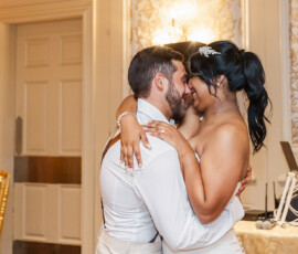 Bride and groom smiling and embracing during their wedding dance in a warmly lit New Orleans reception room.