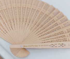 Engraved wooden wedding fan with decorative cutouts on white surface, a charming Louisiana keepsake.