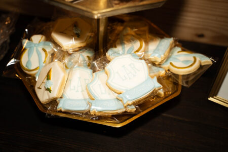 Decorated cookies with blue and white icing labeled “Liar” and “Admit it” on a gold tray, wrapped in clear plastic.