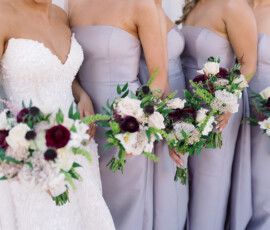 Bride in white lace and bridesmaids in lavender hold bouquets at a classic Louisiana wedding; faces not shown.