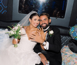 Smiling bride and groom in wedding attire sit closely, showing rings after a joyful Gulf South ceremony.