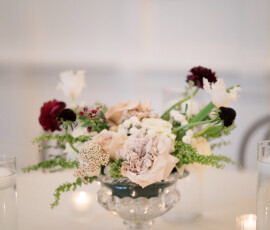 Elegant glass bowl centerpiece with white, blush, and dark red flowers, candles, and water glasses for a Louisiana wedding.