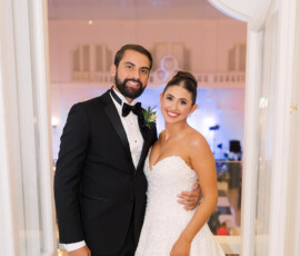 Bride in strapless white gown and groom in black tuxedo pose in bright room with open doors, classic New Orleans wedding.
