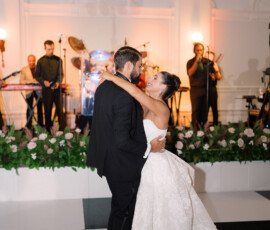 Bride and groom share a joyful first dance on a black and white floor as a live band plays at their elegant Louisiana wedding.