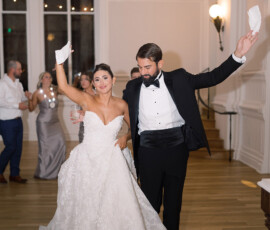 Bride and groom dance, waving white napkins and smiling, with guests celebrating at an elegant New Orleans wedding.