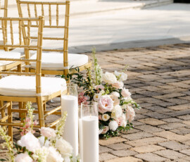 Gold chairs face a candle-lit stone path with pastel flowers, creating a dreamy New Orleans outdoor wedding scene.