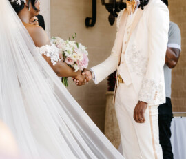Bride and groom in white hold hands at their wedding; bride wears a long veil and holds bouquet—ideal Louisiana wedding inspo.