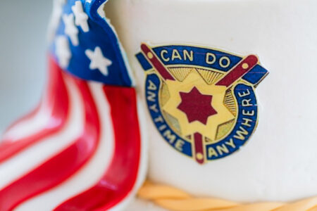 Cake with American flag and blue-yellow “CAN DO ANY TIME ANYWHERE” badge, ideal for Louisiana wedding inspiration.