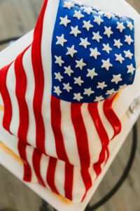 Cake decorated as a waving American flag with red and white stripes, blue stars—ideal for patriotic New Orleans weddings.