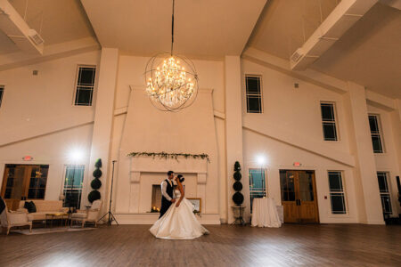Bride and groom’s first dance in an elegant hall with high ceilings, chandelier, tall windows, and classic New Orleans style.