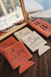 Personalized Seth & Ashley koozies and others with P and B initials on a wooden table, stylish New Orleans wedding inspiration.
