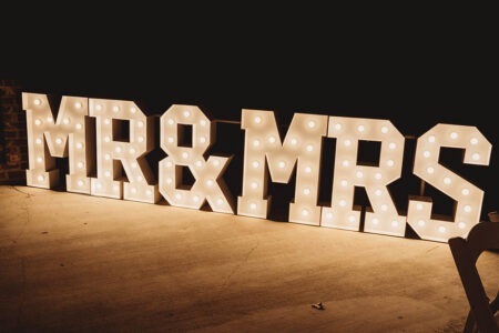 Illuminated MR & MRS marquee letters on a concrete floor stand out against a dark background at a Louisiana wedding event.