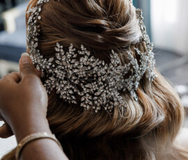 Adjusting a sparkling, floral jeweled headpiece on wavy light brown hair for a stylish New Orleans wedding.