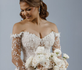 Bride in off-the-shoulder lace dress holds white and pale pink rose bouquet, smiling softly—timeless New Orleans wedding style.