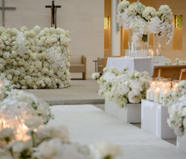 Church interior set for a Louisiana wedding with white flowers, candles, and a cross behind a floral altar.