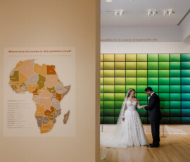 Bride and groom in an art gallery with colorful grid art and Africa map, celebrating a vibrant New Orleans wedding.