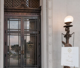 Elegant glass door with metal frames, stonework accents, vintage lamp, and event sign welcome guests to a Gulf South wedding.