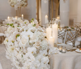 Wedding table with cascading white roses, orchids, tall arrangements, and glowing candles for a romantic Louisiana celebration.