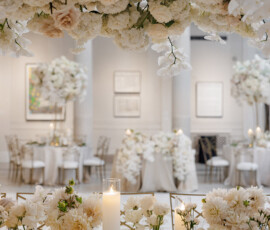 Louisiana wedding reception with long tables, white flowers, tall candles, and gold-accented decor in a bright, elegant room.