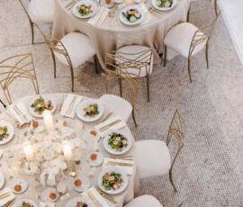 Louisiana wedding reception with round tables, gold chairs, cream linens, salads, bread rolls, candles, and white floral centerpieces.