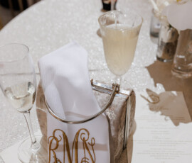 Elegant table with champagne glasses, silver purse, monogrammed napkin, menu, and white orchids at a New Orleans wedding.