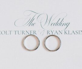 Two silver wedding bands on a white invitation card reading The Wedding Colt Turner & Ryan Klasing in elegant fonts.