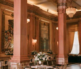 Luxurious ballroom with chandeliers, columns, gold chairs, round tables, and floral centerpieces for a Louisiana wedding.
