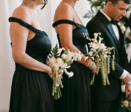 Bridesmaids in black dresses with white bouquets and a groomsman in tuxedo at an elegant New Orleans wedding ceremony.