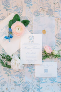 Wedding invitation suite with floral accents, wax-sealed envelope, RSVP card on light blue floral fabric—elegant New Orleans wedding.