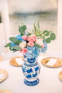 Blue and white vase with hydrangeas and roses on a round table set for an elegant Gulf South wedding.