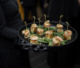 Passed shrimp hors d’oeuvres served on a black tray during cocktail hour at an upscale wedding reception.