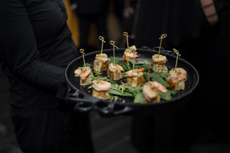 Passed shrimp hors d’oeuvres served on a black tray during cocktail hour at an upscale wedding reception.