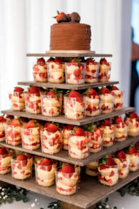 Tiered stand with strawberry shortcake parfaits in clear cups and a chocolate cake—ideal for a Louisiana wedding.